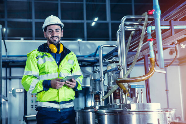 Happy engineer male worker working in factory using tablet computer to check boiler water pipe in factory, portrait smile.