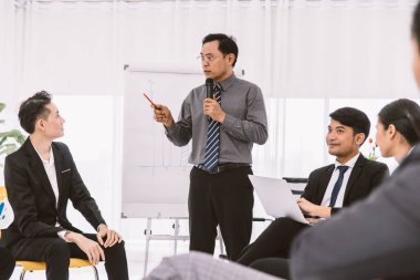 Asyalı iş adamı toplantısı ya da şirket konferansı satış raporu hedef tartışması. Profesyonel yönetici iş planlaması ve eğitimi için genç personelle konuşuyor.