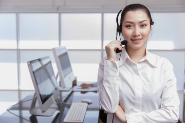 Asyalı kadın portresi. İş yeri çağrı merkezi operatörü. Yardım masası telefon destek ekibi çalışanı genç bayan tebessüm mikrofon kulaklığıyla. Telesale pazarlama temsilcileri.
