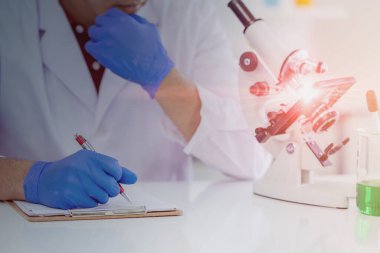 Bilimsel tıbbi araştırma notları için not alan ve düşünen yakın bilim adamları tıp laboratuarında listeleme yapıyor..