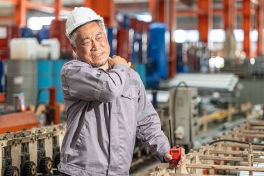 Kıdemli işçi yorgun kas ağrısı ağır sanayi fabrikasında omuz ağrısı çekiyor..