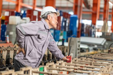 Asyalı kıdemli işçi kas ağrısı, sırt ağrısı, iş yerinde sağlık sorunu, ağır sanayi fabrikasında sıkı çalışma.