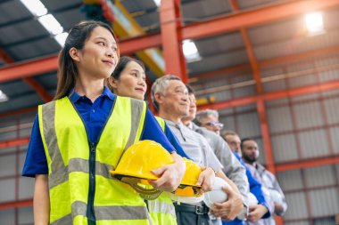 Bir grup işçi, ağır sanayi fabrikasında çalışırken mutlu bir şekilde ayakta duran ırkı birbirine karıştırıyor.