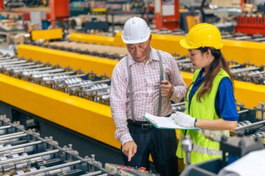 Fabrikada üst düzey yönetici ile çalışan kadın işçiler metal yaprak fabrikasında çalışma düzenini kontrol ediyorlar.