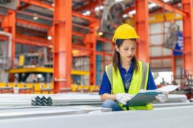Genç Asyalı kadın mühendis, profesyonel çalışan. Metal levha fabrikasında ürün envanterini kontrol ediyor.