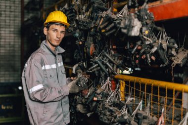 Mühendis teknisyen erkek işçi güvenlik kaskı ile eski makine bölümü deposunda stokları kontrol ediyor..