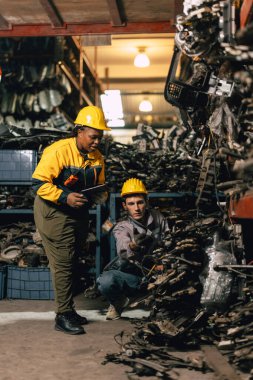 Mühendis personeli olan Afrikalı kadınlar birlikte çalışıyorlar. Ağır endüstri, eski, kullanılmış metal makine, yarı stok deposu..