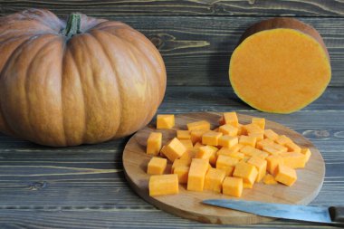 Kahverengi ahşap arka planda balkabağı ve balkabağı parçaları.