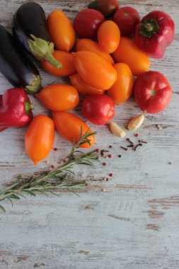 Tahta yüzeyde sarı ve kırmızı domatesler, biberler, sarımsak ve baharatlar var..