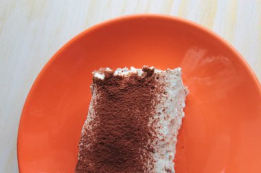 Portakal tabağında böğürtlen ve çikolatayla süslenmiş bir parça pasta..