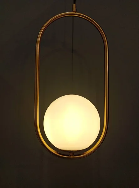 Decorative round lamp on a metal frame on a dark background.
