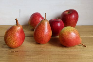 Kırmızı armutlar ve elmalar kahverengi ahşap bir yüzeye uzanıyorlar..