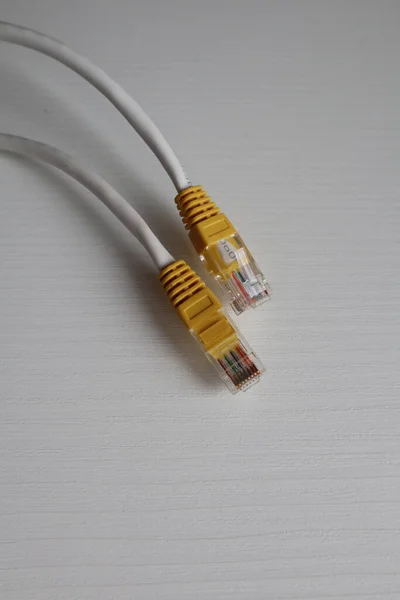 A white cable with a yellow chip on the end of the wire, lying on the table