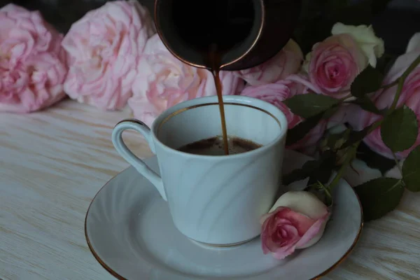 Кофе Наливают Тюрка Белую Кружку Фоне Розовых Роз — стоковое фото