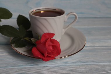 Bir kupa çay ve masanın üstünde kırmızı bir gül..