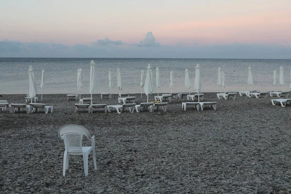 Morgendämmerung Strand Leere Liegestühle Und Geschlossene Sonnenschirme Strand lizenzfreie Stockfotos