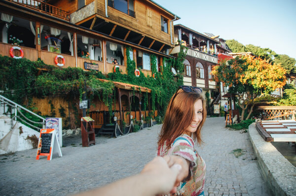 Девушка ведет на прогулку по улице с древними деревянными зданиями в Старом городе Несебр
