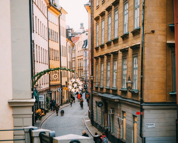 STOCKHOLM, SWEDEN - MARCH, 18, 2015: Tourists walk along the narrow street of the old town (Gamla Stan) with cafes, bars and souvenir shops