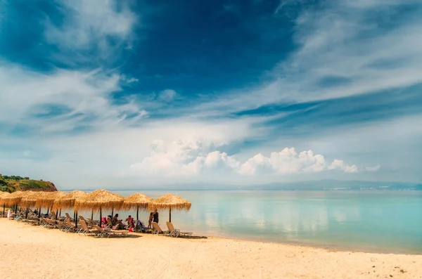 Halm paraply, solsängar på en strand i Grekland — Stockfoto