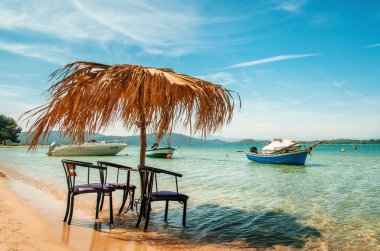 Turkuaz denizde thatched şemsiye altında sandalye