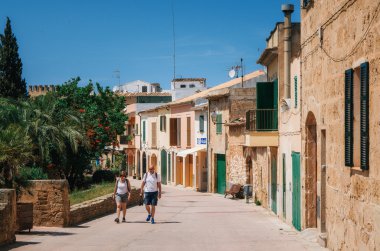 Turistler, Alcudia tarihi kent parçası geleneksel ev ve ağaçlar boyunca yürüyüş