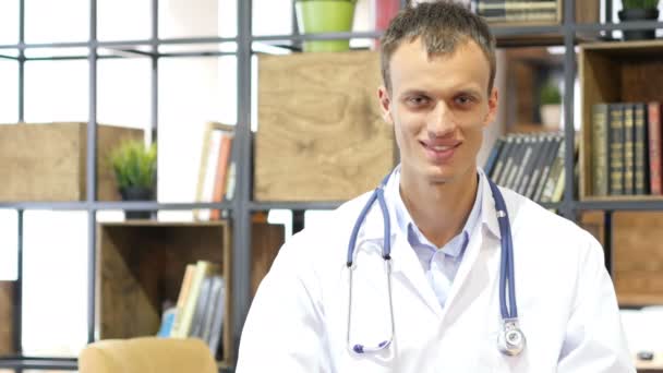 Retrato del joven doctor sonriendo a la cámara en un consultorio en el hospital — Vídeo de stock