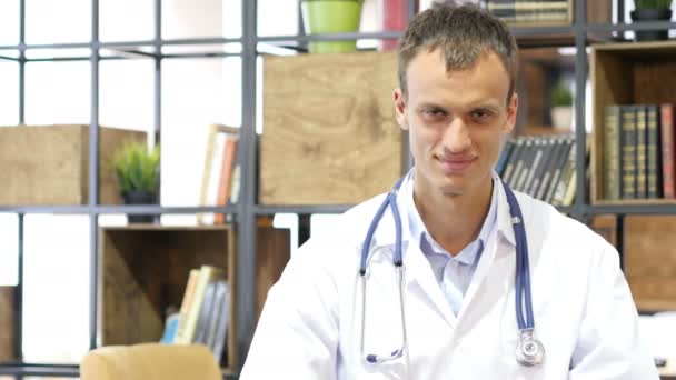 Joven médico exitoso mostrando los pulgares hacia arriba en el consultorio n hospital — Vídeos de Stock