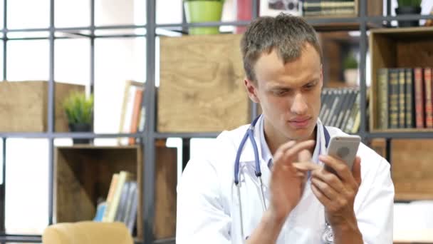 Доктор использует свой смартфон в офисе — стоковое видео