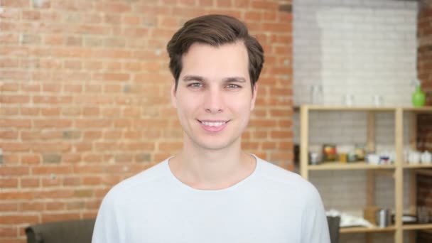 Portret van zelfverzekerde jonge man glimlachend en permanent in zijn kantoor — Stockvideo