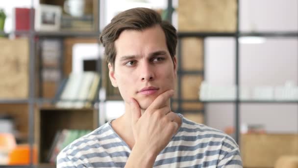 Portrait de jeune créatif assis au bureau et travaillant pendant qu'il pense le sol — Video