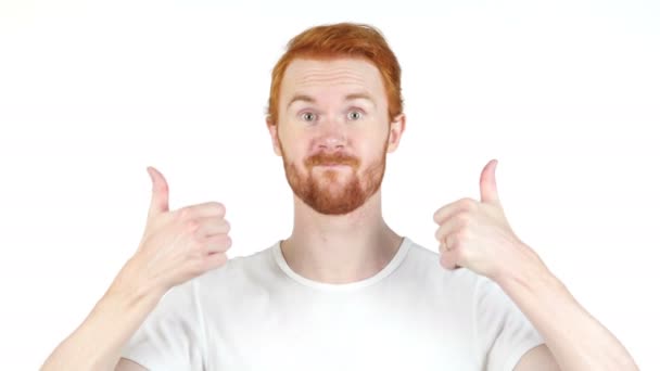 Alegre vermelho cabelo homem polegares até posando e sorrindo para a câmera, branco fundo — Vídeo de Stock