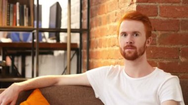 genç adam onun çalışma evinde otururken gülümseme ile kameraya bakan