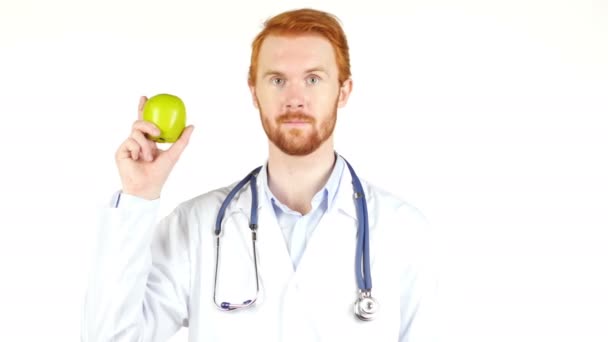 Retrato de un médico mostrando una manzana con el pulgar hacia arriba, fondo blanco — Vídeo de stock