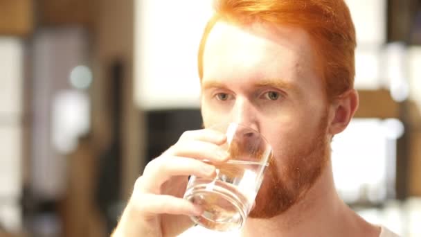 Prachtige jonge man is gezond te houden door het drinken van een glas water binnenshuis — Stockvideo