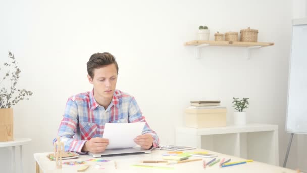 Diseñador hombre pasando por el papeleo en la oficina, comprobar el nuevo proyecto — Vídeos de Stock