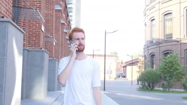 Chodící muž mluví o telefonu w / podkroví budovy zázemí, pohled zepředu — Stock video
