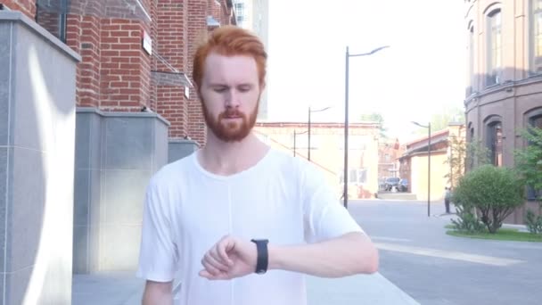 Uomo che cammina utilizzando Smartwatch w / Loft Building Background, Vista frontale — Video Stock