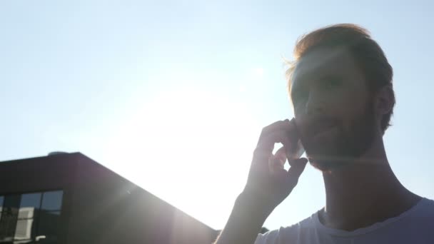 Hablando por teléfono delante del sol, silueta al aire libre — Vídeo de stock