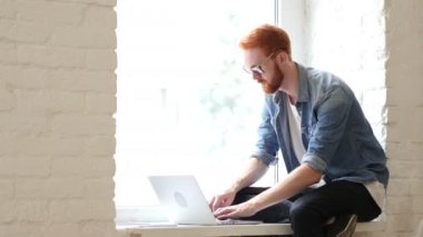 Thumbs Up penceresinde kırmızı saç ve sakal ile oturan adam, çalışarak