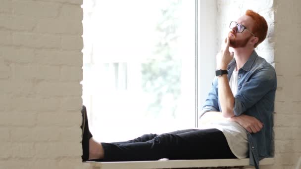 Gondolkodás tervező, ül az ablakban, vörös haj és szakáll — Stock videók