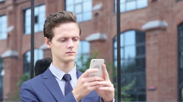 Uomo d'affari Utilizzando Smartphone per la ricerca di informazioni, in piedi all'aperto — Video Stock