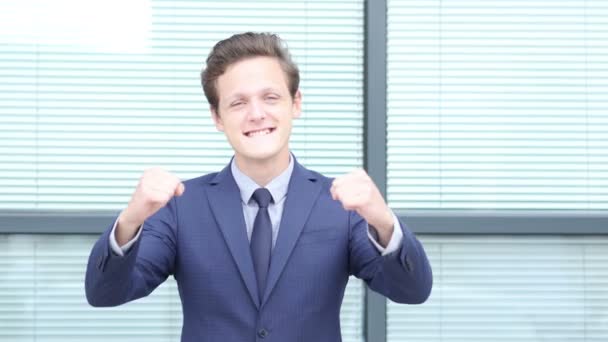 Возбужденный молодой бизнесмен празднует успешное завершение проекта — стоковое видео