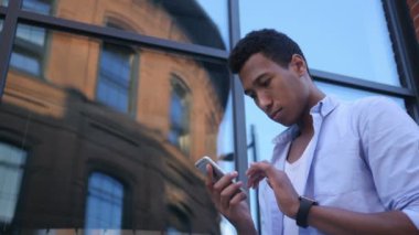 Genç siyah erkek tasarımcı ayakta Smartphone, kullanarak meşgul