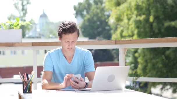 Solig dag, med hjälp av Smartphone medan sitter utomhus på jobbet — Stockvideo