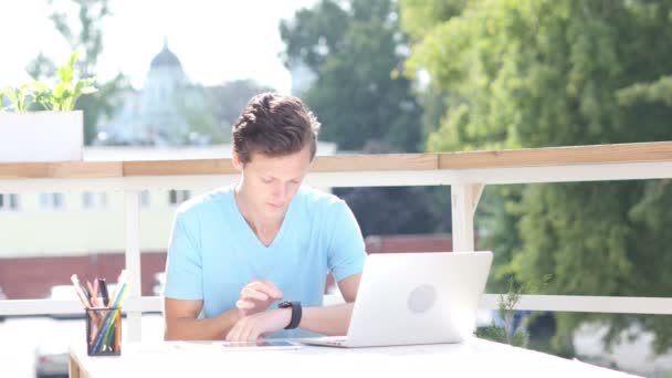 Sonniger Tag, Mann sitzt und benutzt Smartwatch auf Balkon, Gadget — Stockvideo