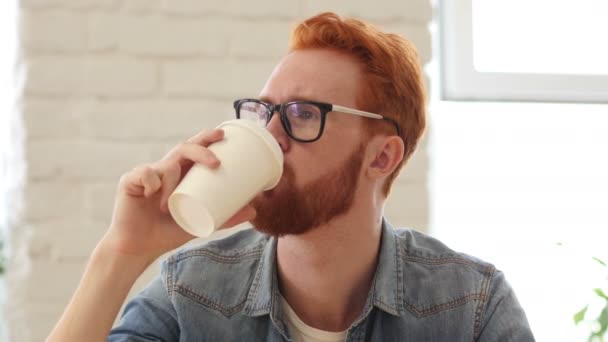Человек с бородой и рыжими волосами, пьющий кофе, чай в офисе, портрет — стоковое видео