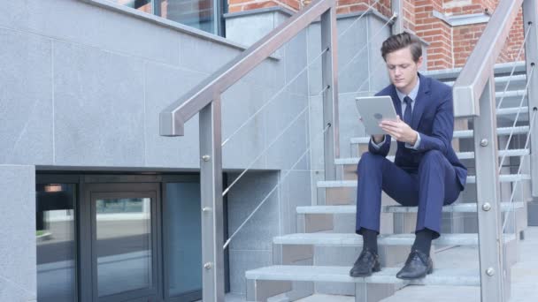 Junger Geschäftsmann mit Tablet, Browser, sitzt auf der Treppe vor dem Büro — Stockvideo