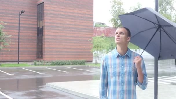 Frustrado com o tempo, em pé sob guarda-chuva durante a chuva — Vídeo de Stock