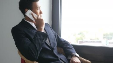 Telefon meşgul siyah işadamı takım alan içinde oturup, konuşurken