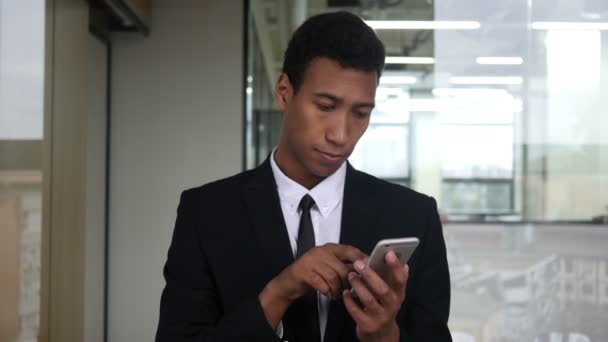 Surfen auf dem Smartphone, schwarzer Geschäftsmann im Büro — Stockvideo